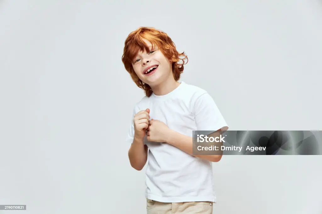 Ragazzo dai capelli rossi che sorride con le mani davanti a sé